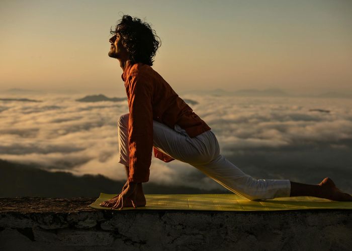 Silhouette of a man stretching against a sunrise.